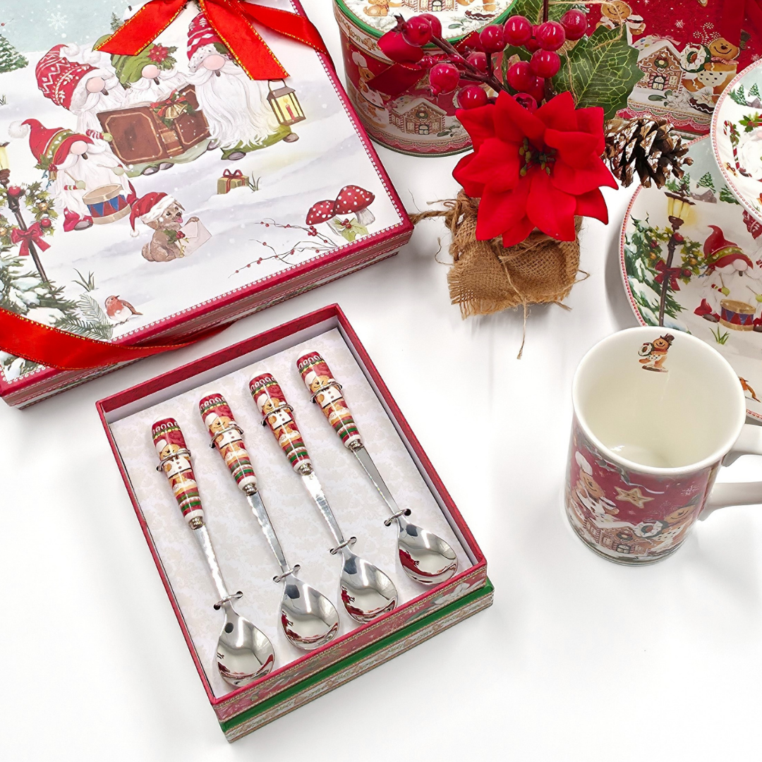 Coffret de quatre cuillères de Noël avec manches décorés rouges, présenté dans une ambiance festive avec décorations et vaisselle de Noël.