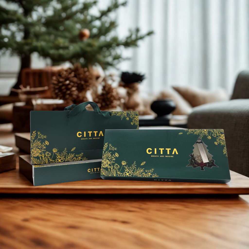 Coffret CITTA de sapins parfumés en cire posé sur une table en bois dans une ambiance de Noël chaleureuse.