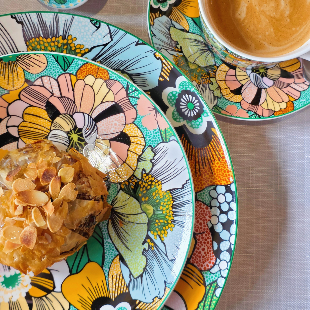 Gros plan sur assiette en porcelaine motif floral coloré avec pâtisserie et tasse assortie.