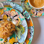 Gros plan sur assiette en porcelaine motif floral coloré avec pâtisserie et tasse assortie.