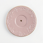 Soucoupe assortie en porcelaine rose avec bordure dorée et motifs calligraphiques arabes.
