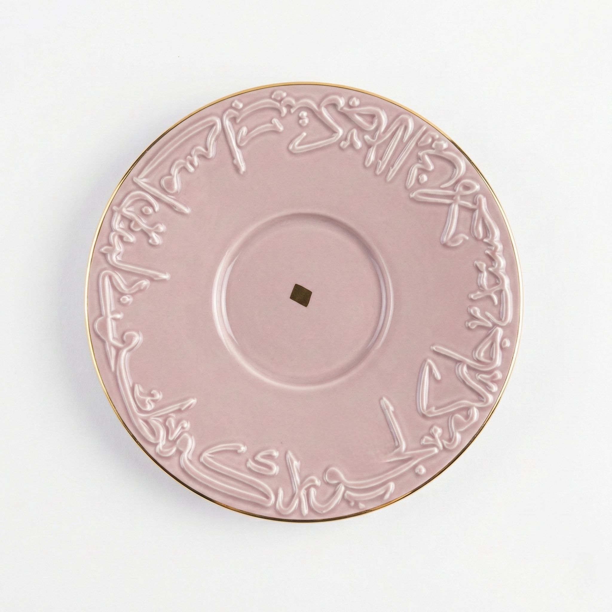 Soucoupe assortie en porcelaine rose avec bordure dorée et motifs calligraphiques arabes.