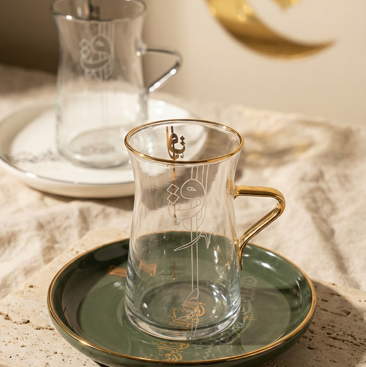 Mise en scène festive de Ramadan avec verres à thé calligraphiés et décoration croissant de lune dorée.