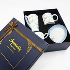 Boîte cadeau ouverte contenant trois pièces en porcelaine décorées d’oiseaux et de fleurs.