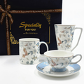 Ensemble en porcelaine avec motifs oiseaux et fleurs devant un coffret cadeau bleu nuit.