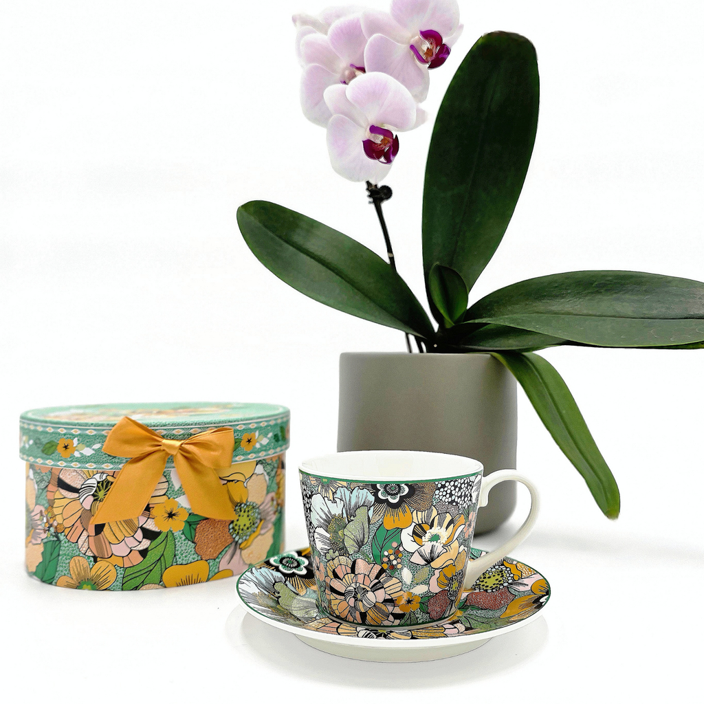Tasse en porcelaine fleurie avec sous-tasse et coffret assorti, présentées avec une orchidée blanche, Collection Majorelle.