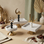 Trio de présentoirs en pierre blanche et or pour le Ramadan sur une table en bois avec lanternes.