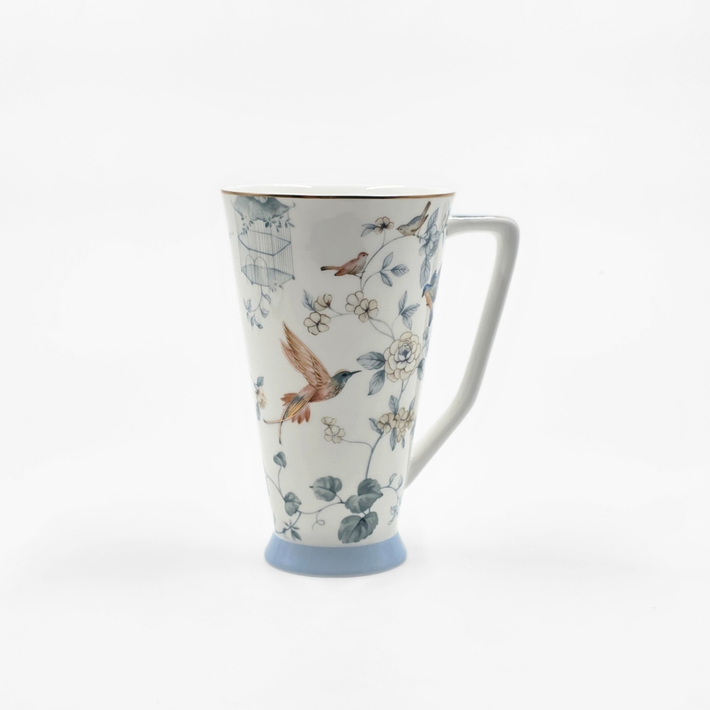 Grande tasse en porcelaine décorée d’oiseaux et de fleurs dans des tons doux.