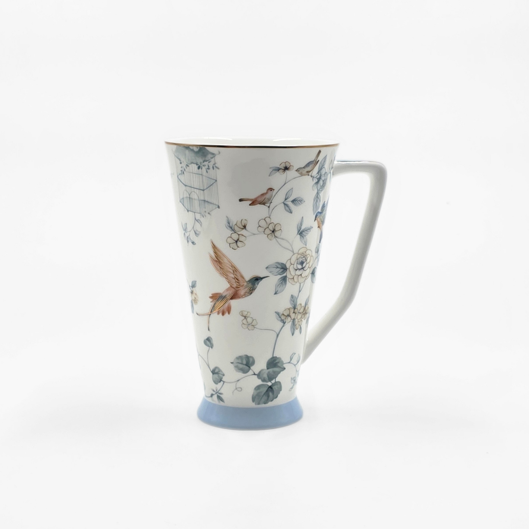 Grande tasse en porcelaine décorée d’oiseaux et de fleurs dans des tons doux.