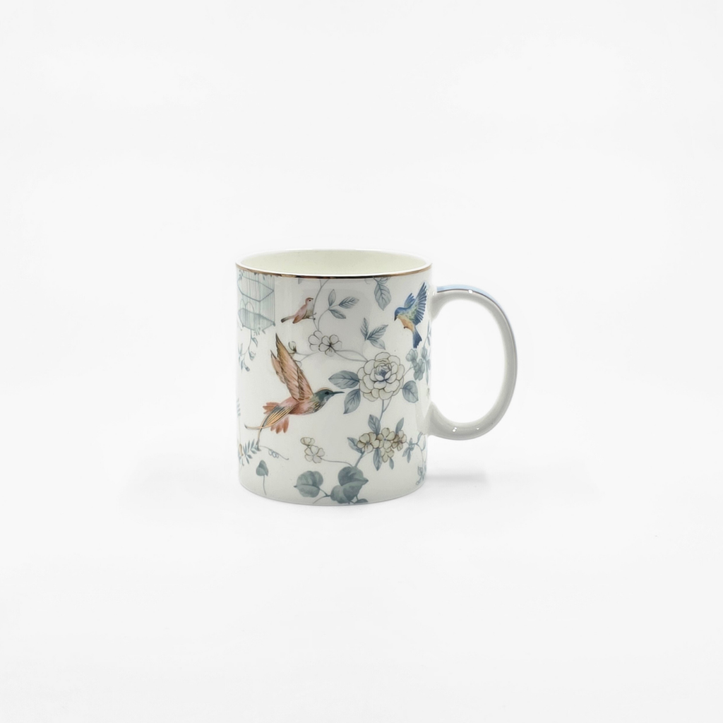 Mug en porcelaine décoré de motifs d’oiseaux et de fleurs sur fond blanc.