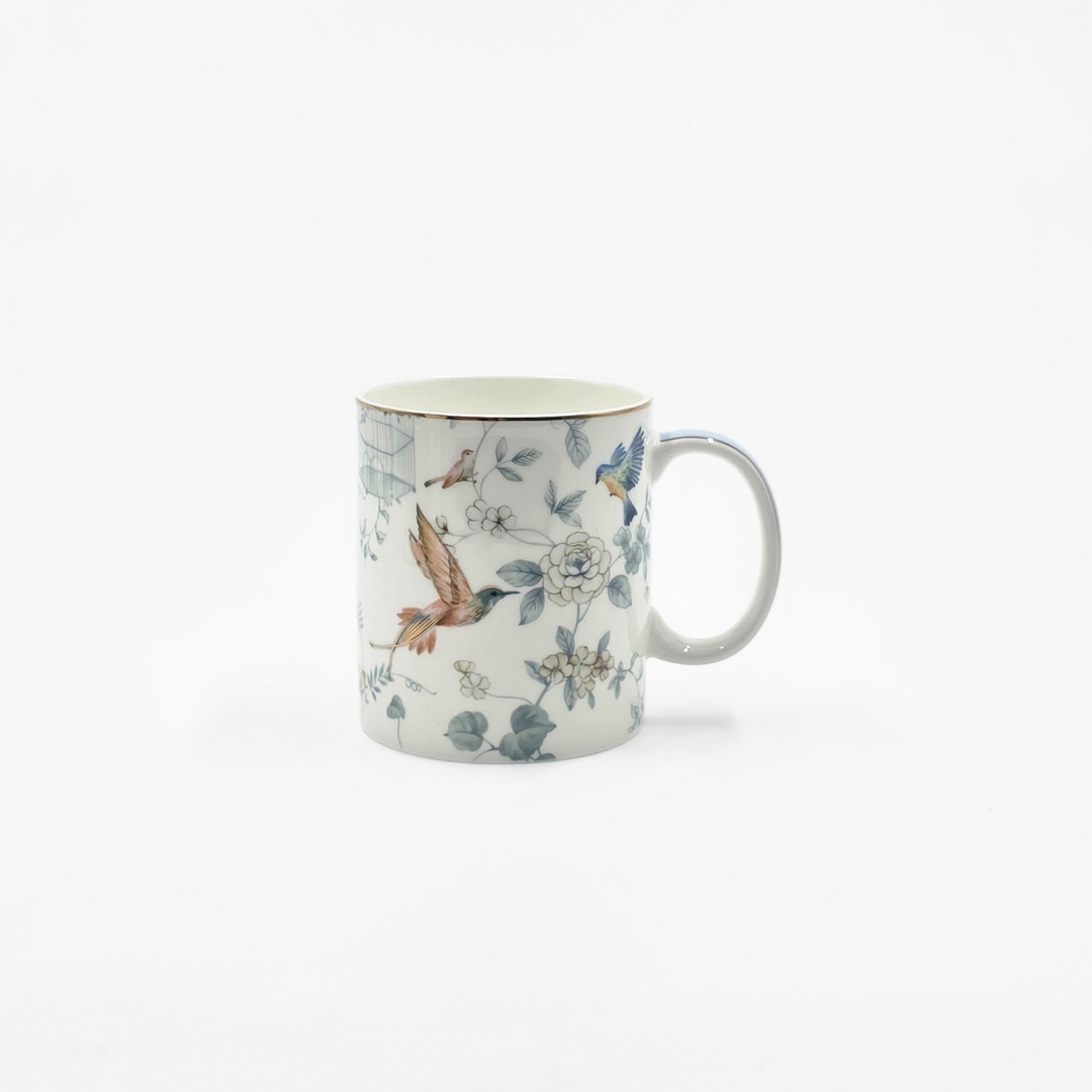 Mug en porcelaine décoré de motifs d’oiseaux et de fleurs sur fond blanc.