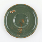 Détail d'une soucoupe vert émeraude avec calligraphie arabe en relief dorée et bordure or.