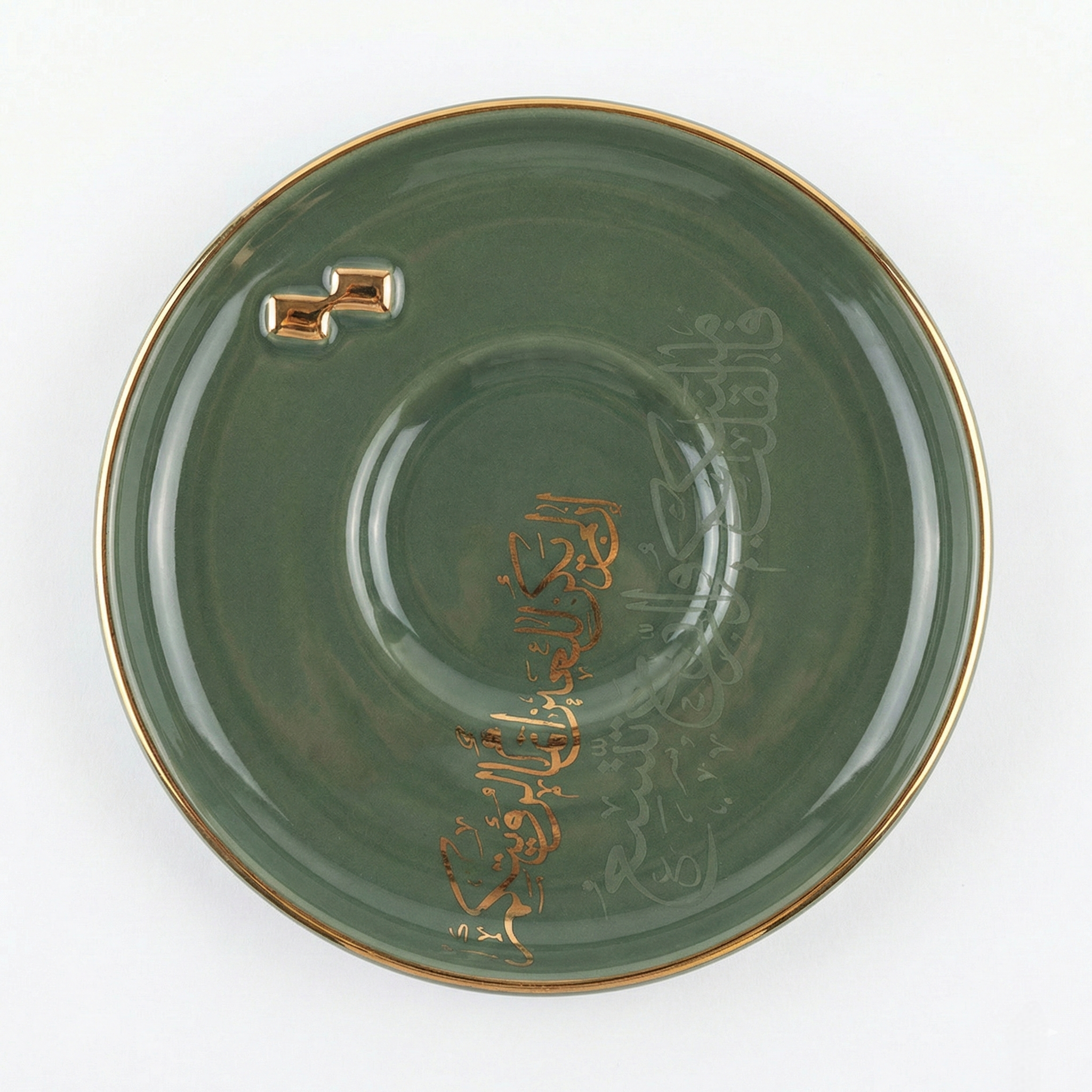 Détail d'une soucoupe vert émeraude avec calligraphie arabe en relief dorée et bordure or.