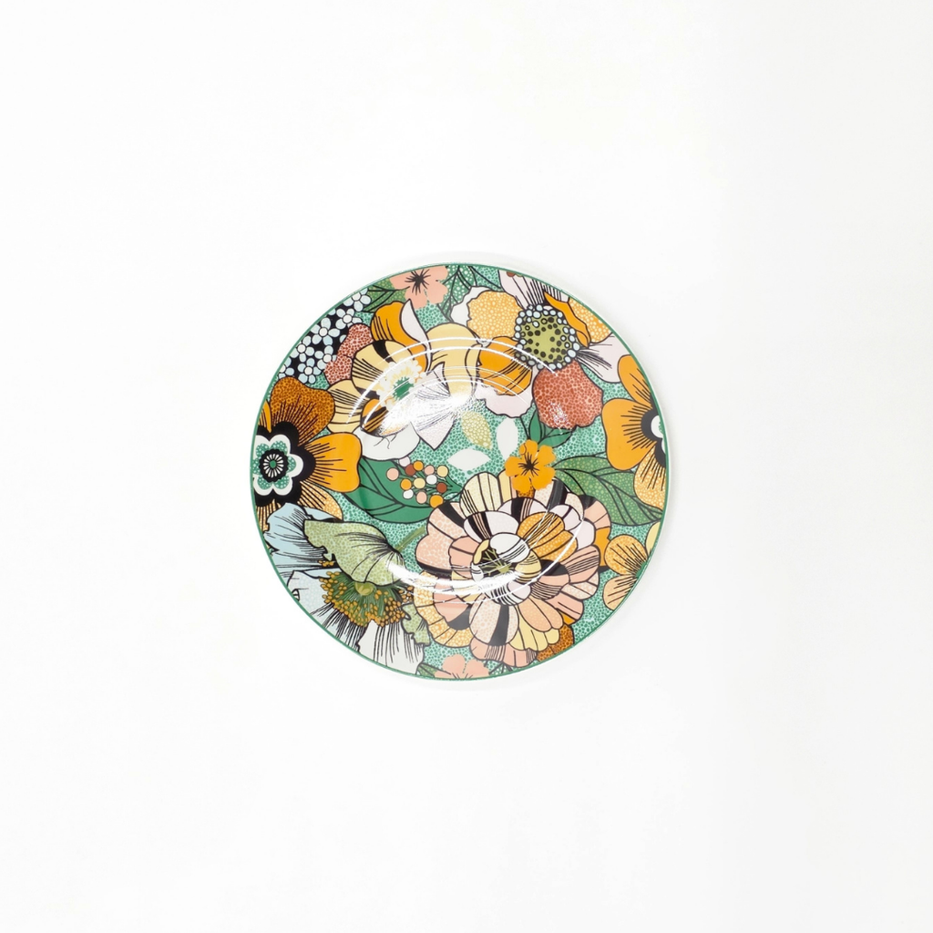 Sous-tasse en porcelaine décorée de motifs floraux colorés, vue du dessus.