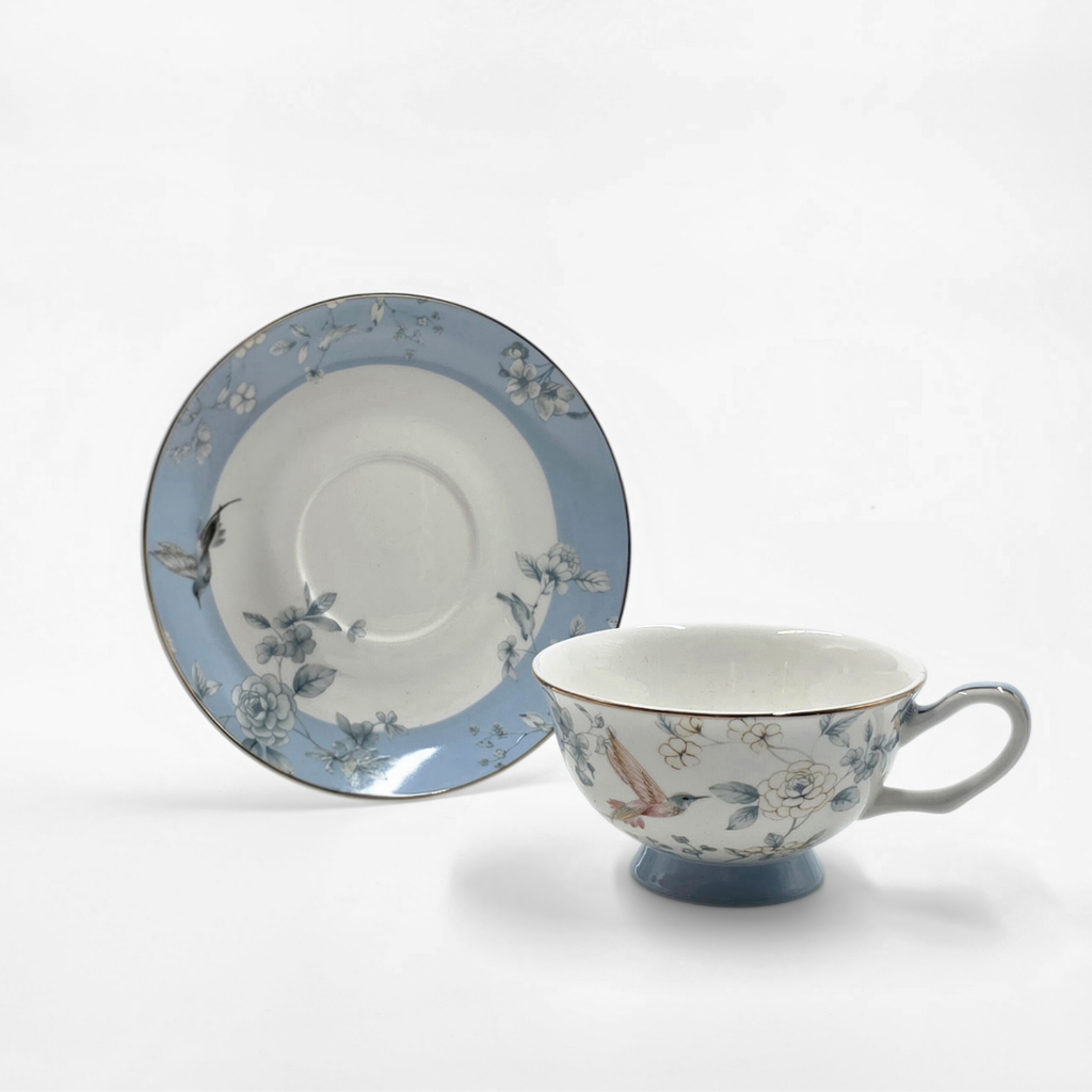 Tasse et soucoupe en porcelaine bleu pastel avec motifs oiseaux et fleurs.