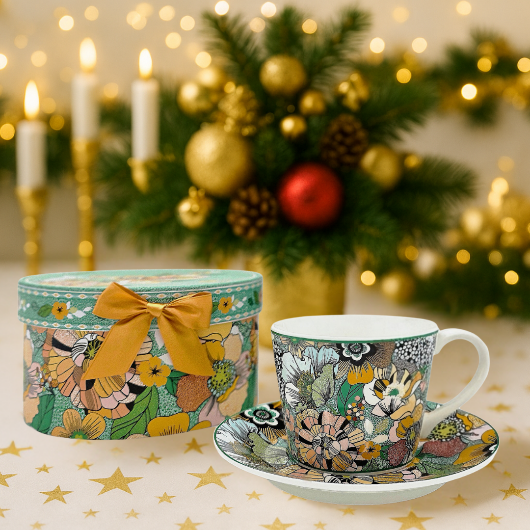 Tasse en porcelaine florale et coffret assorti, mise en scène festive avec décor de Noël doré.