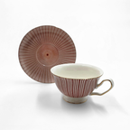Tasse et soucoupe rouges a motif circulaire exposees en gros plan.