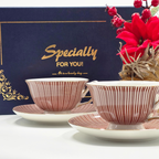 Duo de tasses a the rouge et or devant un coffret cadeau bleu elegant.