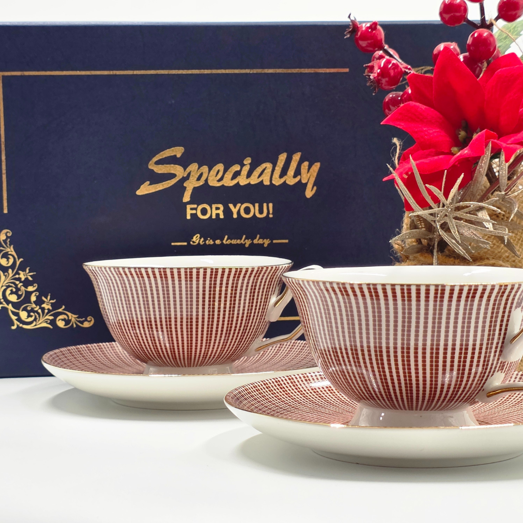 Duo de tasses a the rouge et or devant un coffret cadeau bleu elegant.